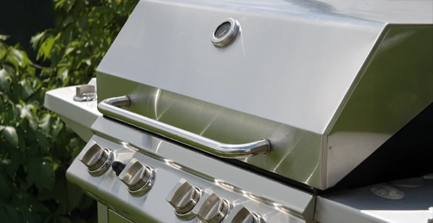 Modern stainless steel gas grill with multiple burner controls for outdoor cooking